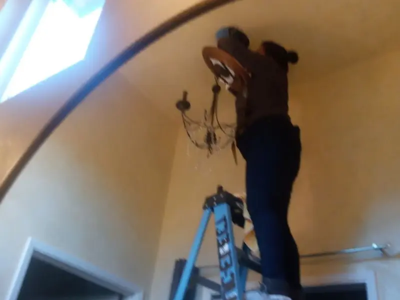 Electrician installing a chandelier in a Hounsfield residence